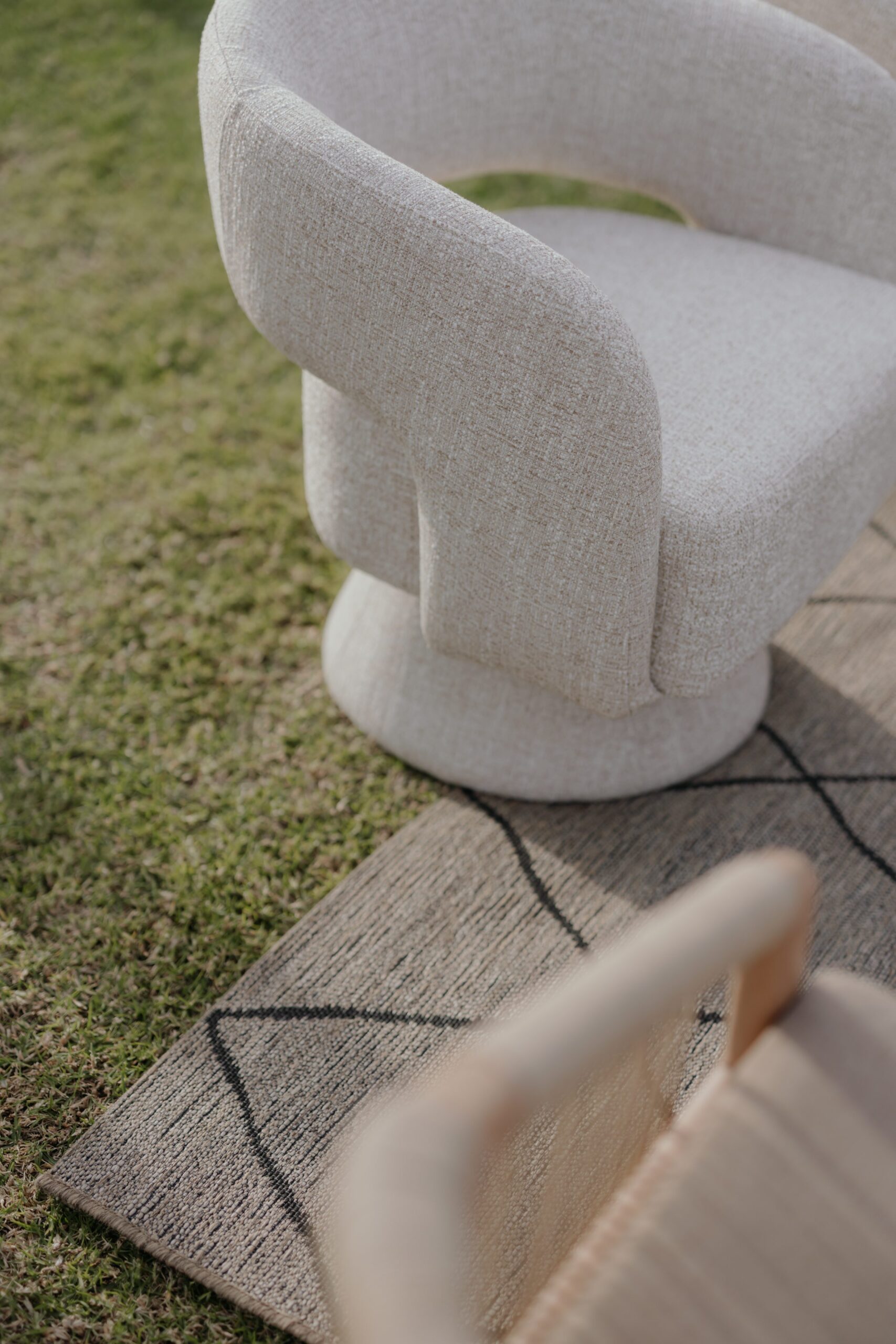 Modern neutral armchair and geometric rug styled for an outdoor event lounge by a|CREATE